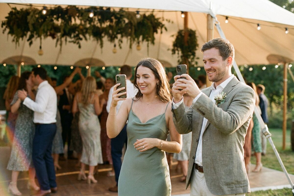 Wedding guests taking photos on their phones at an outdoor reception