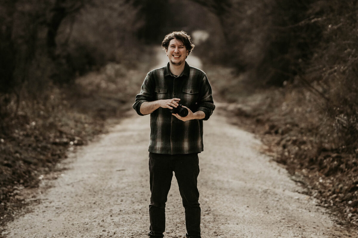 Videographer Jason Lynch standing on a woodland track holding a camera